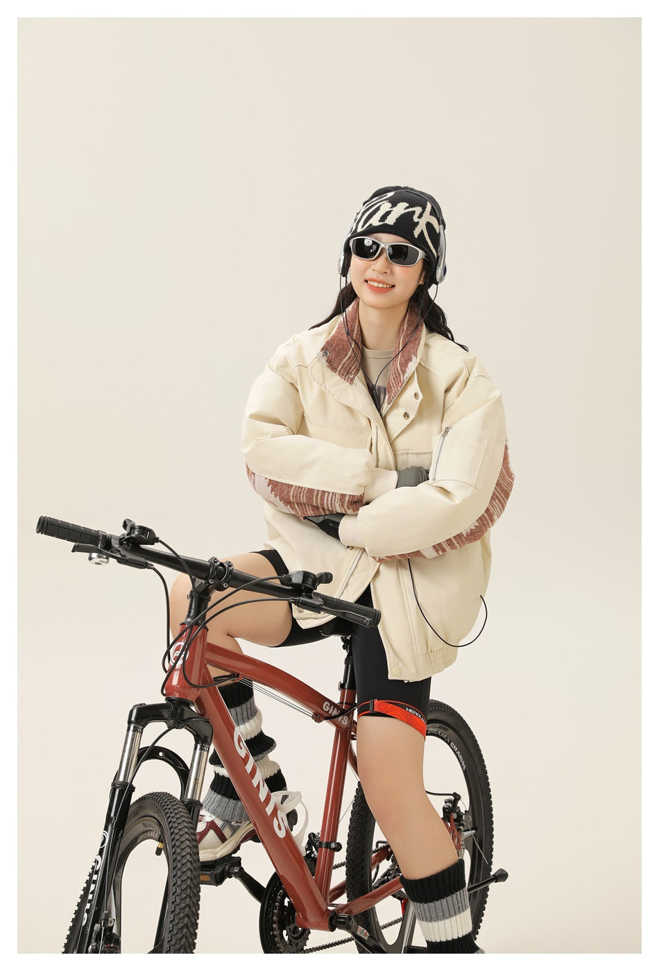 Model seated on a bike in an off-white jacket with a red-brown patterned collar and inner sleeves