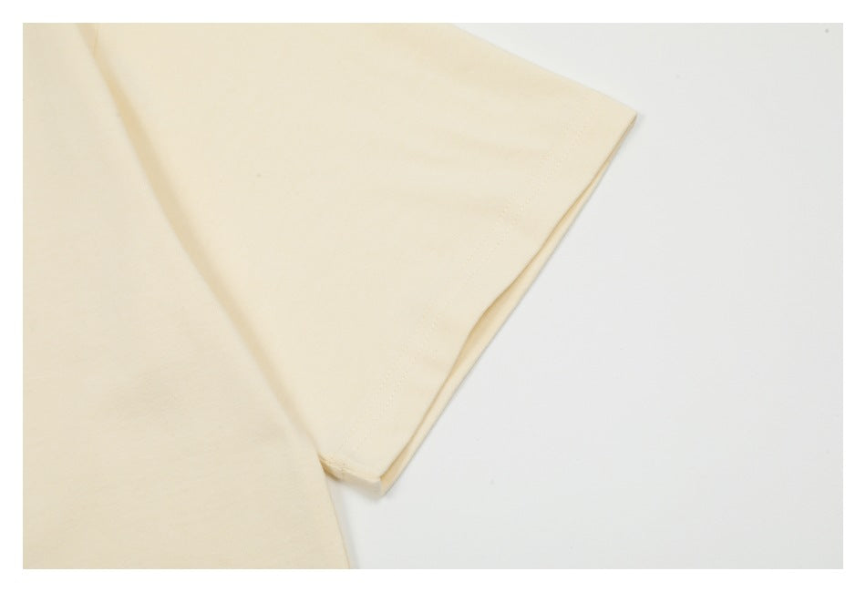 Close-up of the light cream T-shirt sleeve and stitched sleeve hem.