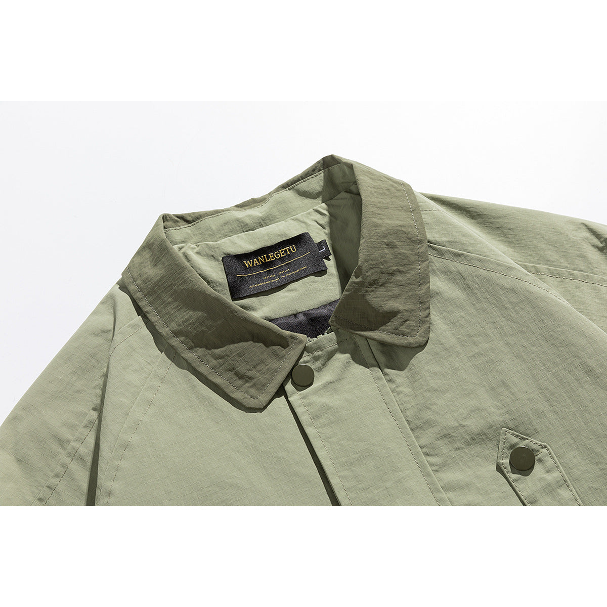 Close-up of an olive-green jacket collar, snap-button placket, chest pocket, and sewn-in neck label.