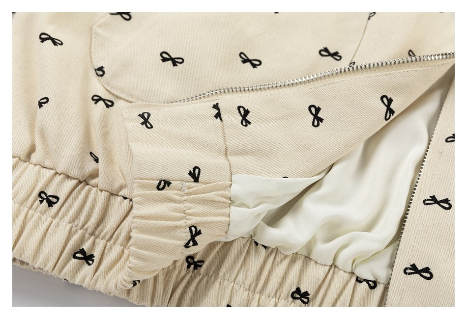 Inside detail of a beige bow-print garment showing a zipper, pale lining, and gathered elastic edge.