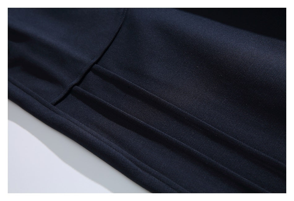Close-up of dark navy pants fabric with a stitched seam and parallel raised folds.