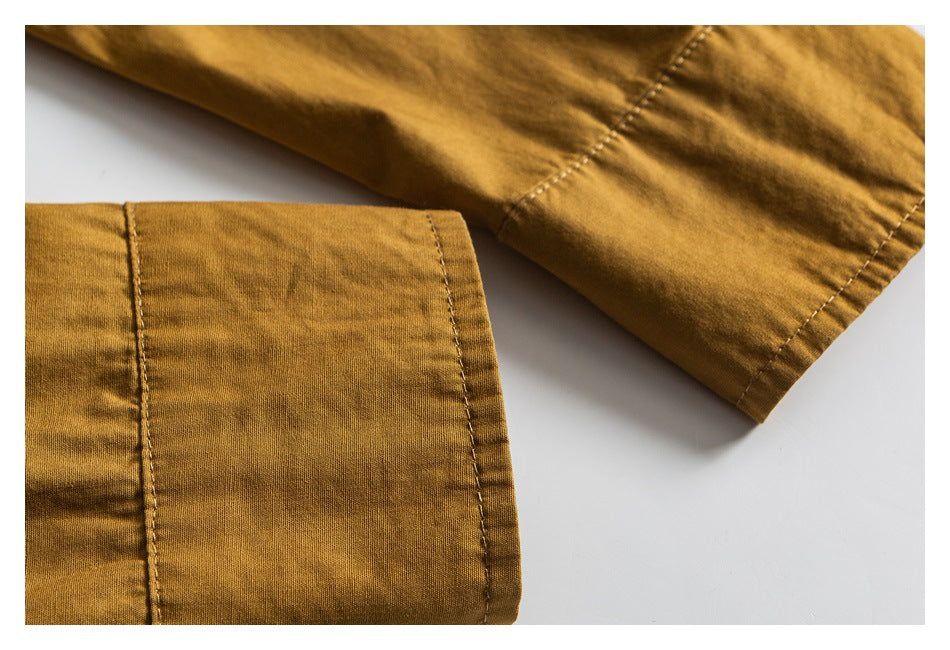 Close-up of a mustard shirt sleeve and wide button cuff, showing the seams and stitching.