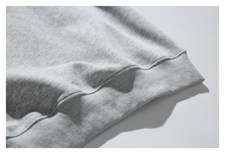 Close-up of the ribbed hem and seam on a heather-gray sweatshirt.