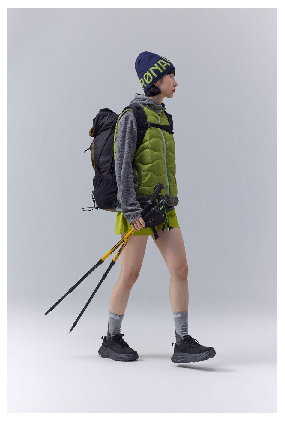 Side view of a model wearing a lime-green quilted vest with hiking gear.