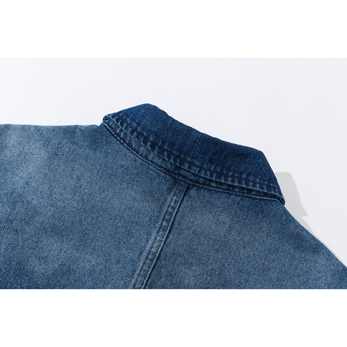Close-up of the back collar and shoulder seam of a blue denim shirt.