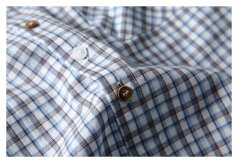 Close-up of a white shirt with blue and brown plaid checks and contrasting buttons on the front placket.