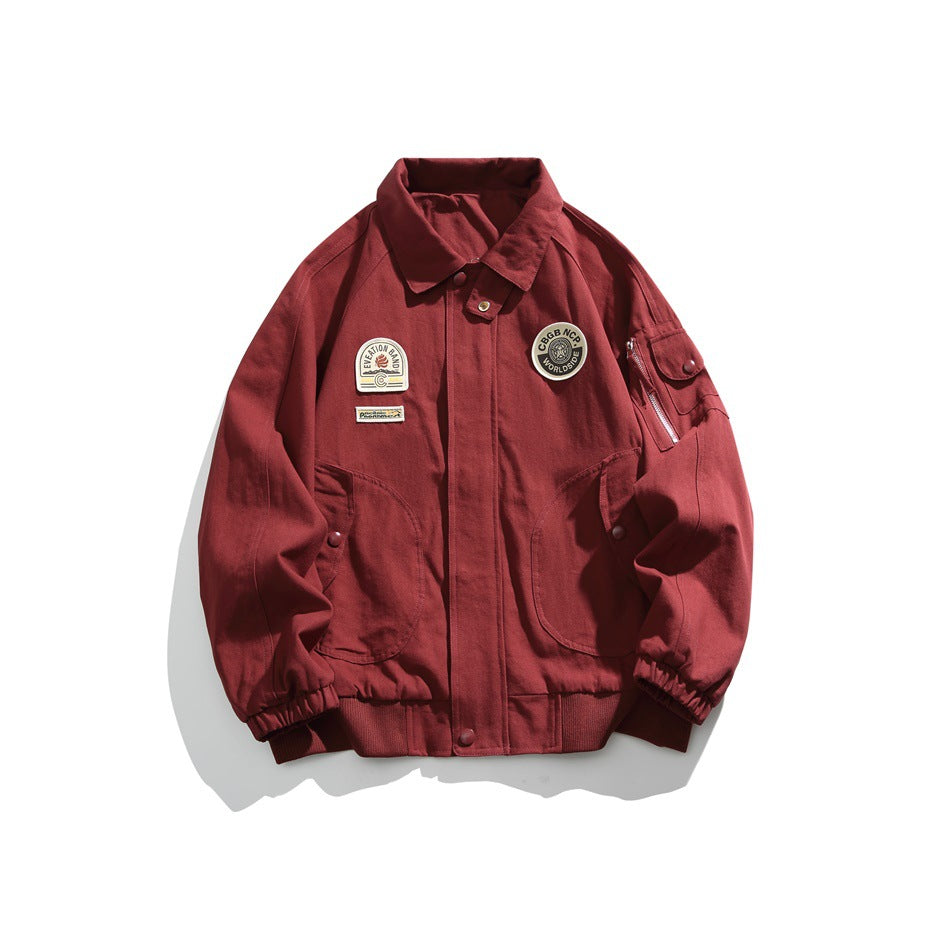 Burgundy bomber-style jacket with fold-down collar, chest patches, curved front pockets and sleeve zip pocket