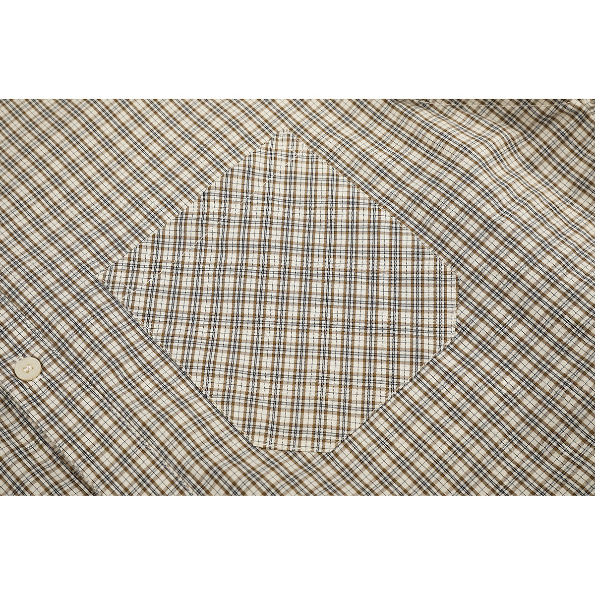 Close-up of a square chest pocket on a beige and brown plaid shirt.