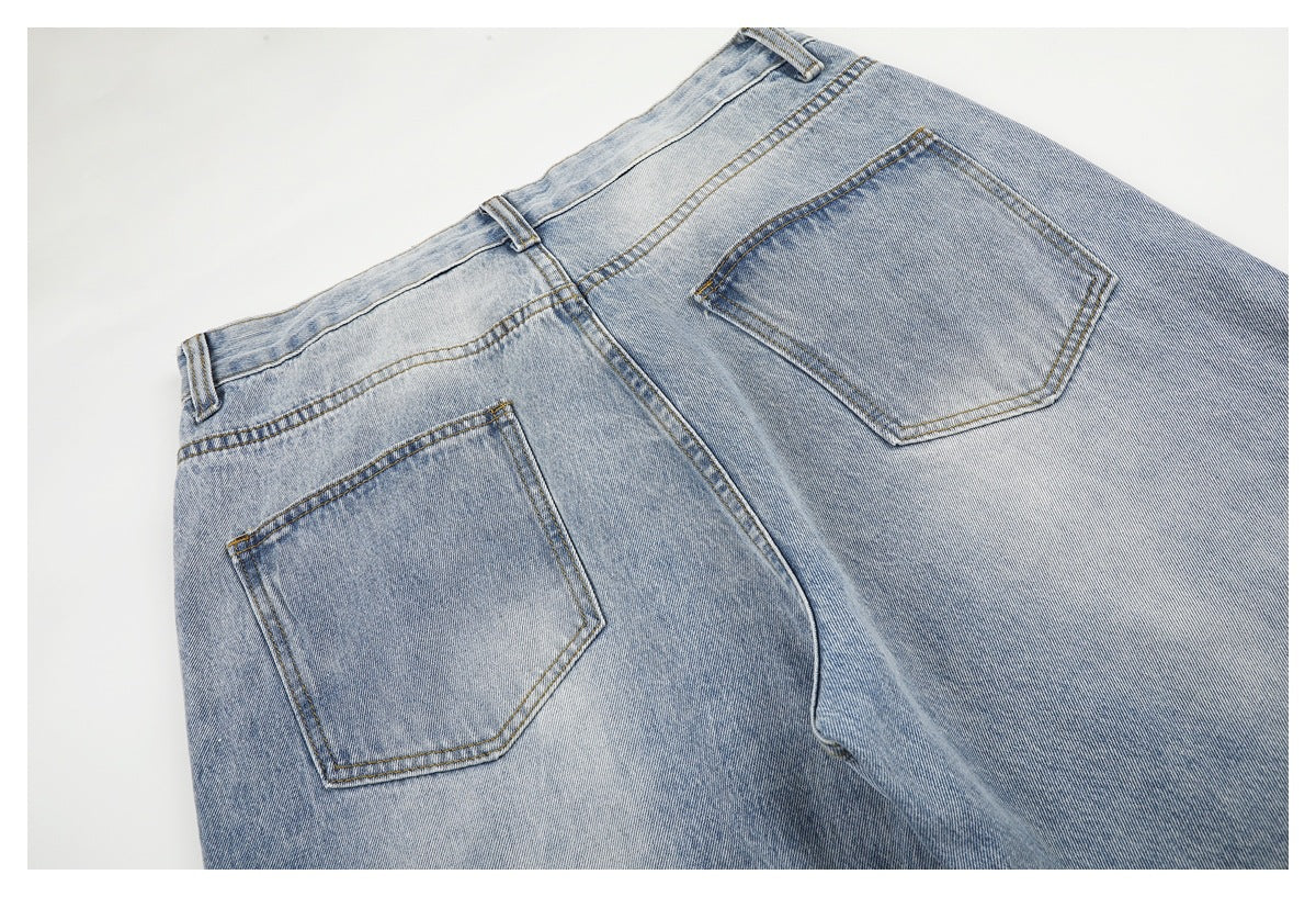 Upper back of light blue washed jeans laid flat, showing the waistband, center seam, belt loops, and two back pockets.