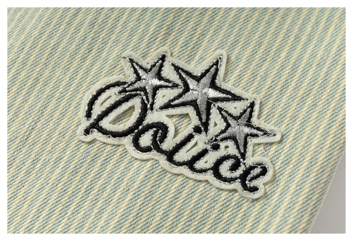 Star-and-script embroidered appliqué on pale blue and cream striped denim.
