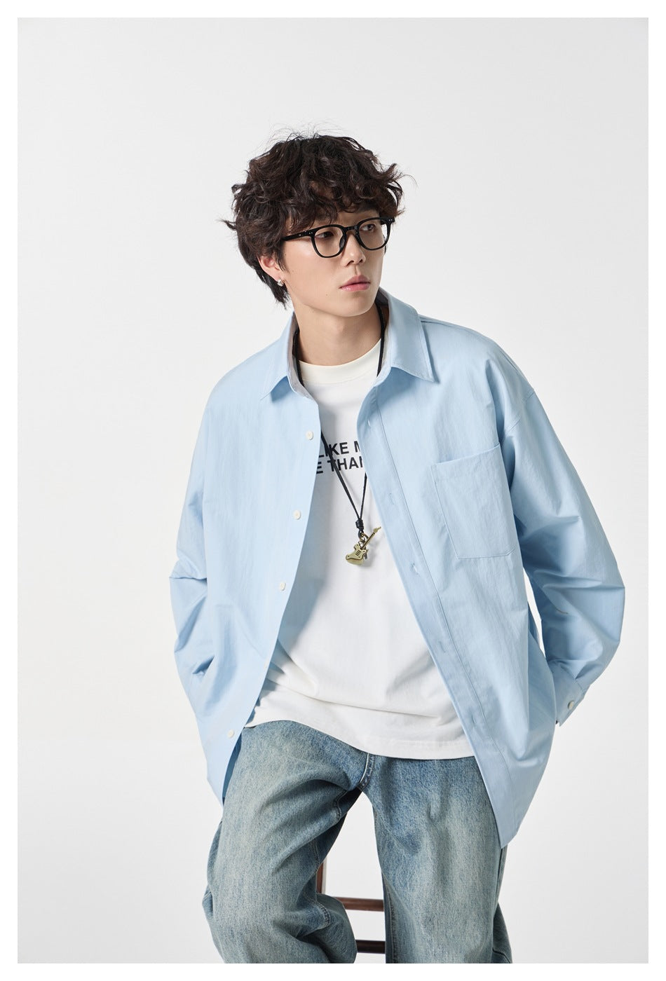 Closer view of a model in an open pale blue button-up shirt with a chest pocket, layered over a white tee.