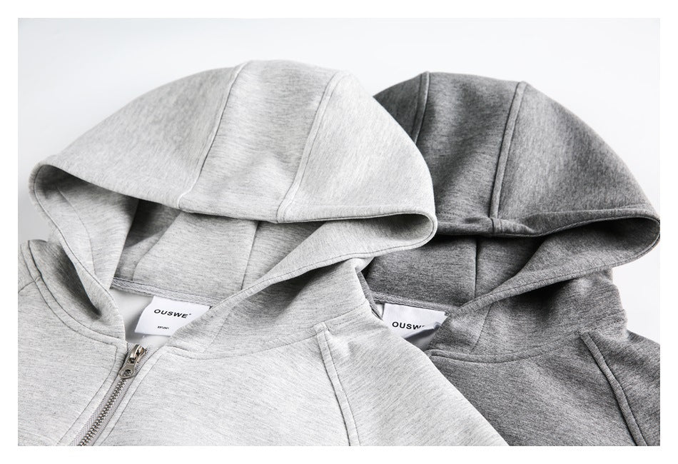 Close-up of the hoods, inner labels, seams, and zipper tops of light and dark gray hooded jackets.