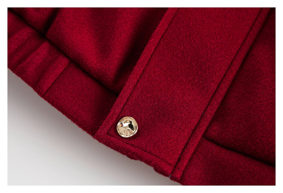 Close-up of a burgundy coat cuff and sleeve tab with a gold-tone button.