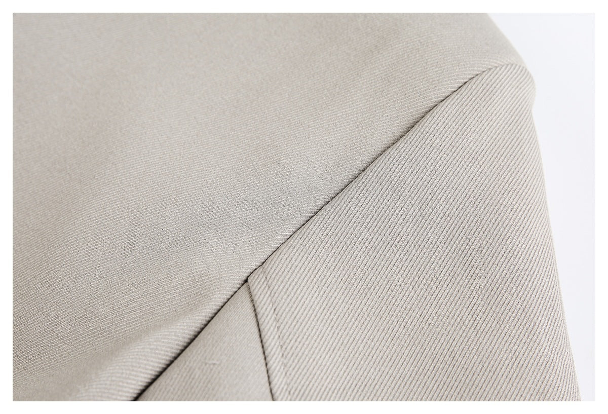 Close-up of a taupe jacket seam and overlapping fabric panels.