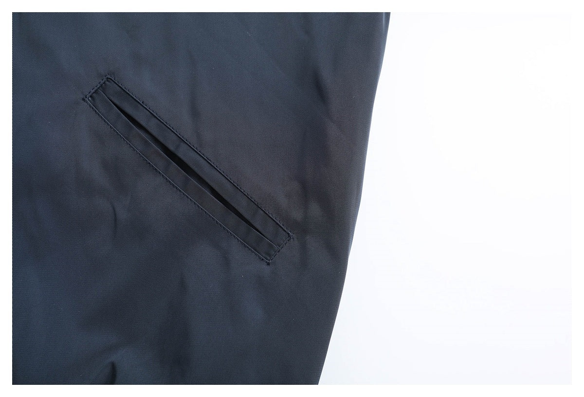 Close-up of a diagonal welt pocket on dark navy garment fabric.