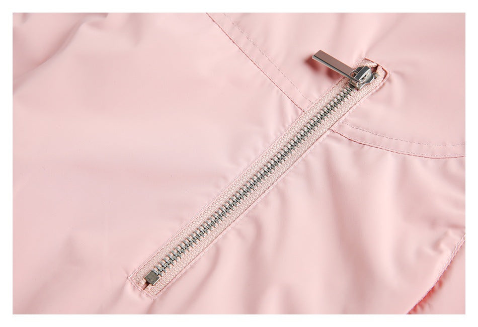 Close-up of a long diagonal metal zipper on pale pink garment fabric.
