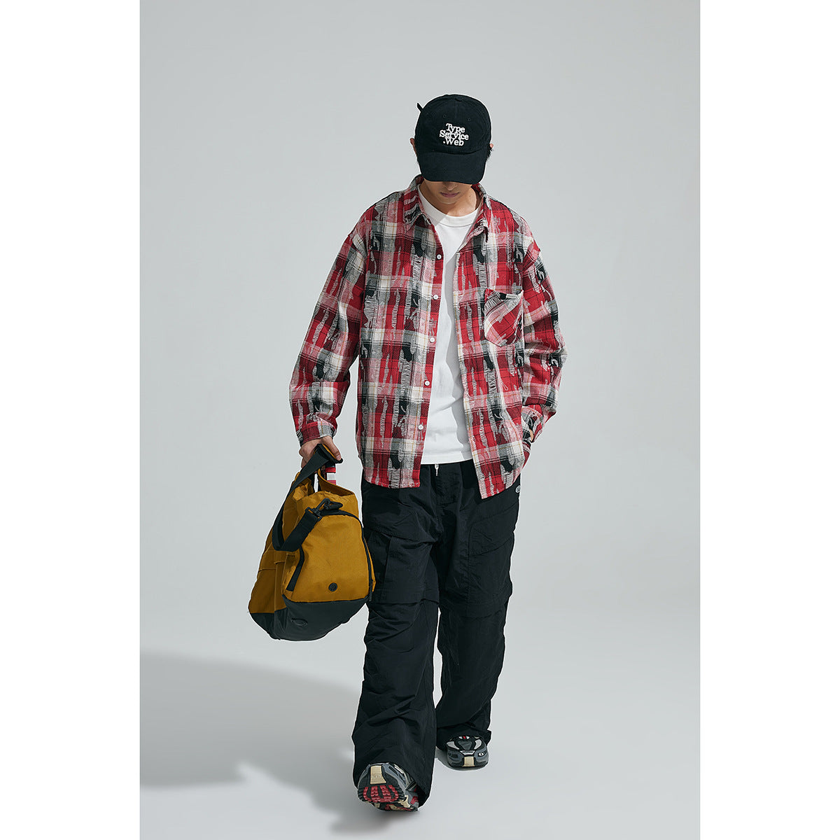 Model wearing an open red, black and white plaid shirt over a white tee, shown from the front.
