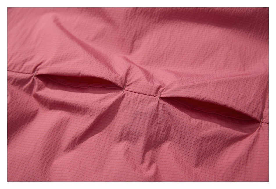 Close-up of two horizontal pocket openings and stitching on dusty rose fabric.
