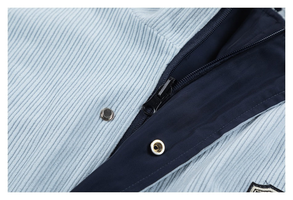 Close-up of a light blue corduroy garment's dark zipper and metal snap fasteners.