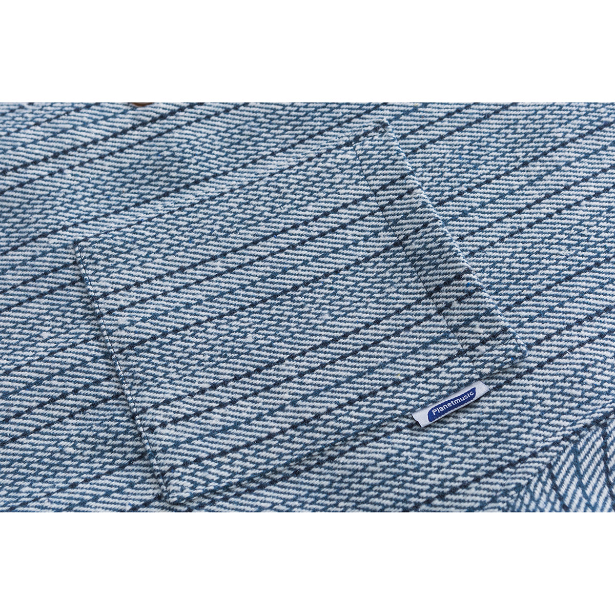 Close-up of blue-and-white striped shirt fabric with seams and a small sewn Planetmusic label.