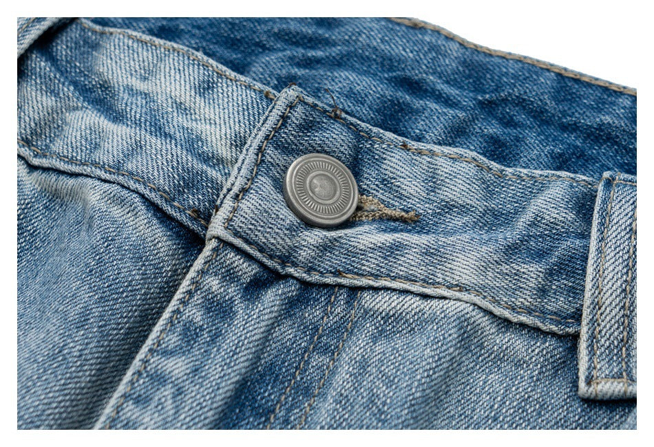 Close-up of the metal waist button and belt loop on light blue jeans.