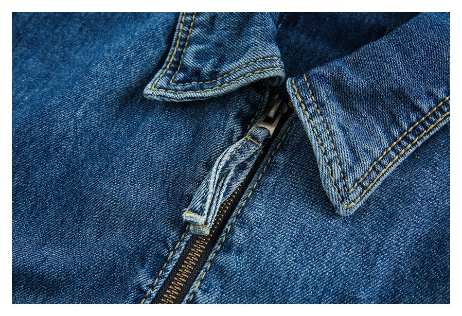 Close-up detail of the denim jacket's metal zipper, collar edges, and contrasting topstitching.