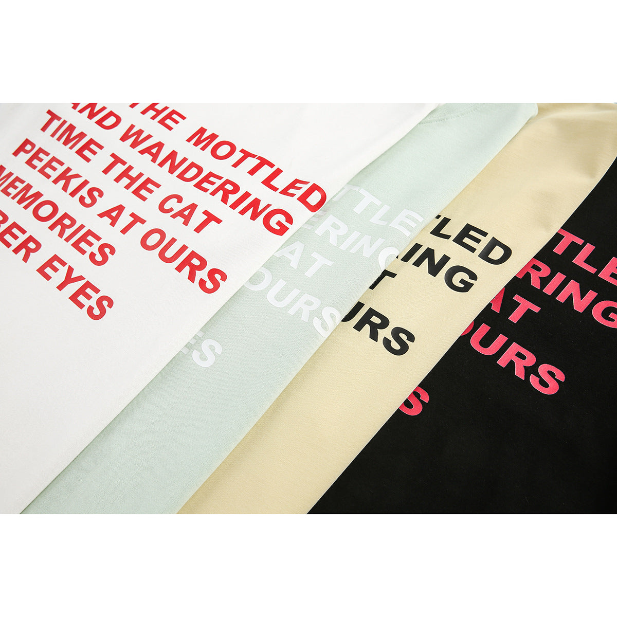 Close-up of English text printed across white, mint, pale yellow, and black T-shirts.