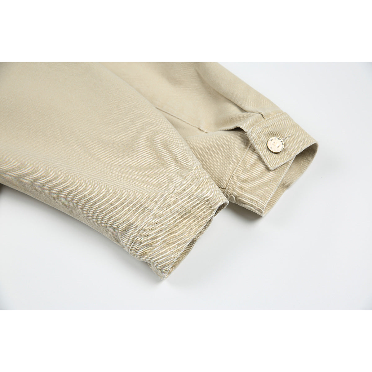 Close view of beige jacket sleeves and cuffs, including a buttoned cuff tab.