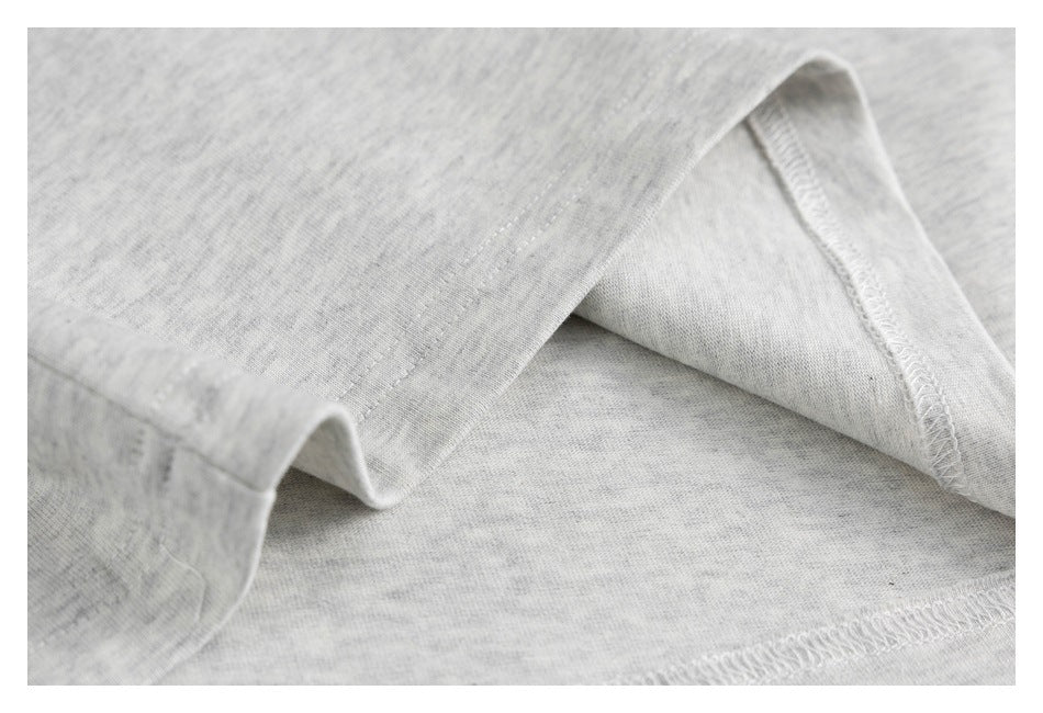 Close-up of light gray heather knit fabric folded to show an overlocked seam and stitching.