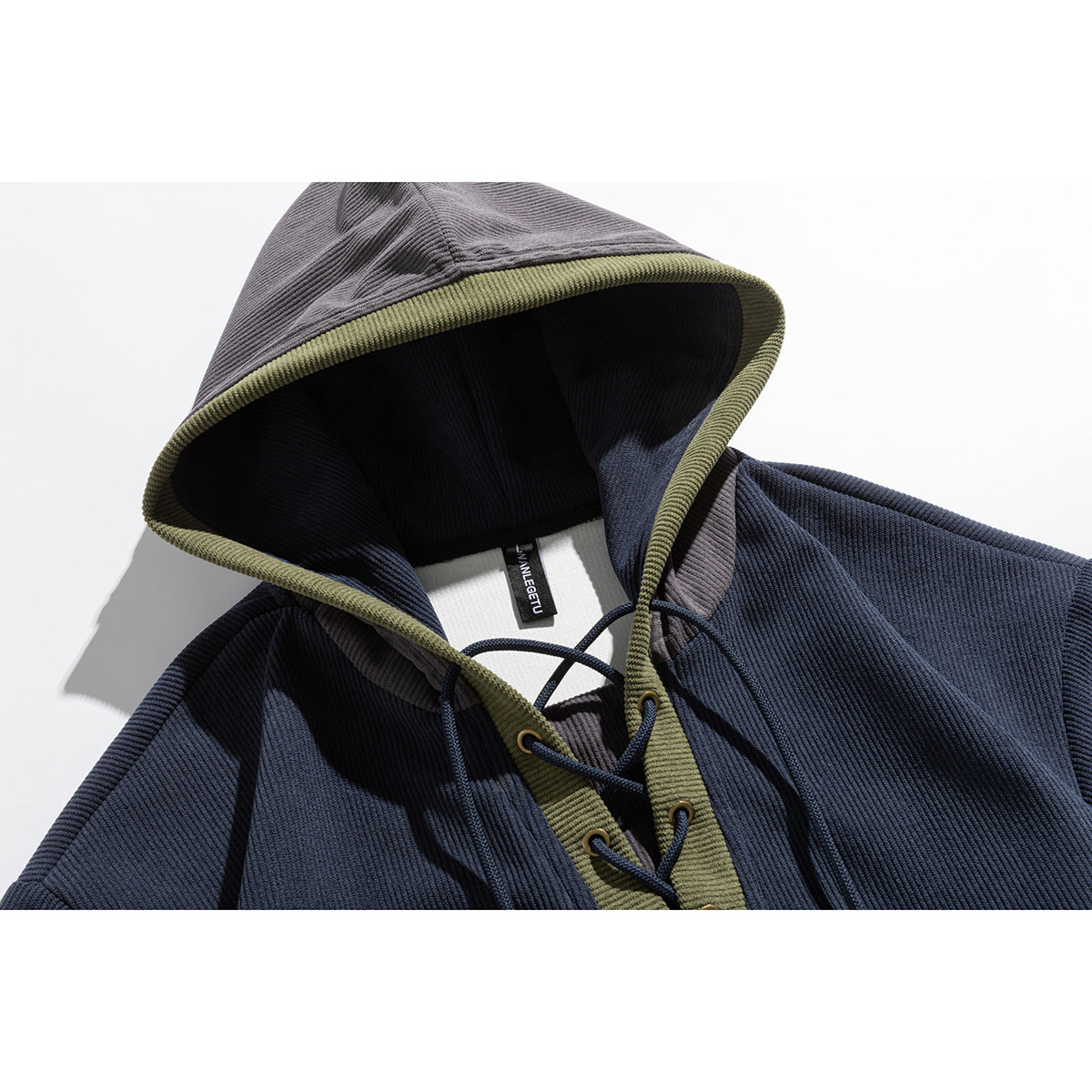 Close-up of a navy hooded pullover with a gray hood, olive edging, and dark drawcords.