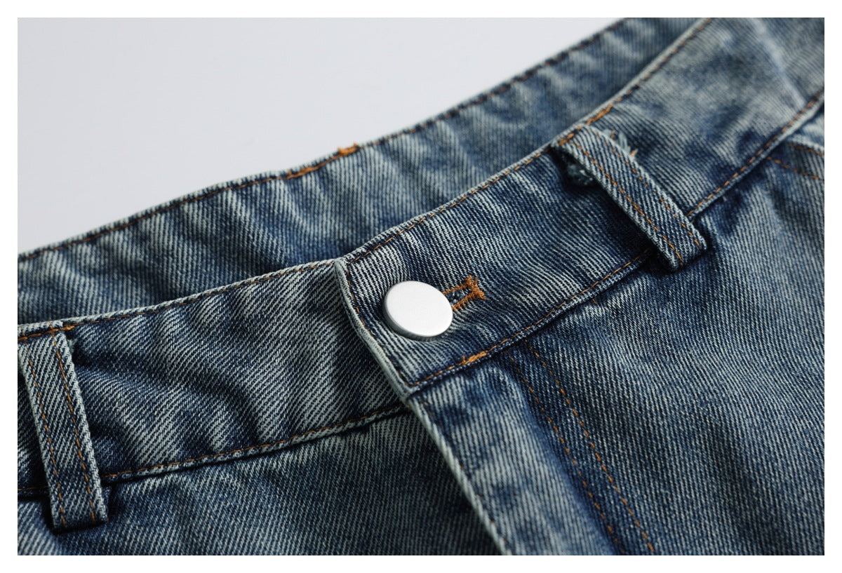 Close-up of the jeans' waistband button, belt loops, fly stitching, and faded blue denim.