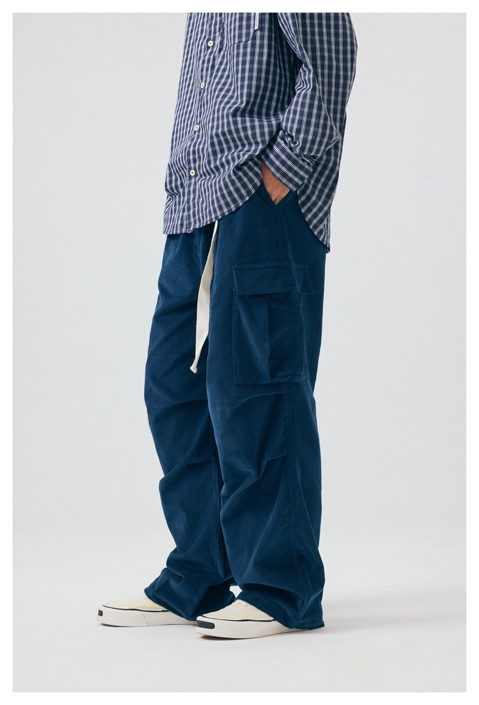 Side view of a model wearing loose navy cargo pants with a flap thigh pocket and a light-colored drawstring.