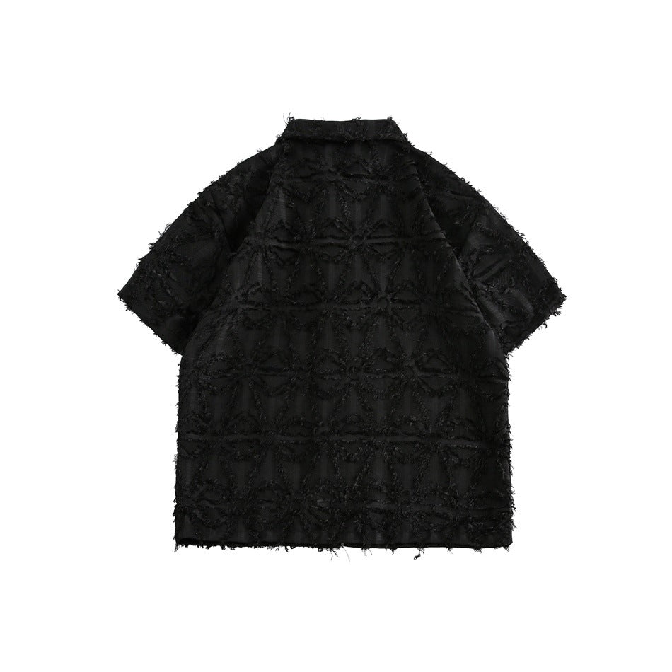 Flat-lay back view of a black short-sleeve collared shirt with a raised geometric pattern and fringed edges.