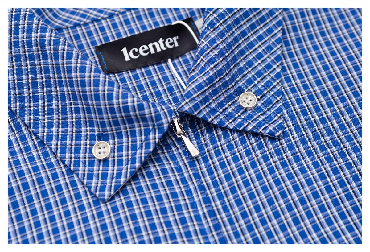 Close-up of a blue plaid shirt collar, buttons, zipper pull, and sewn black neck label.