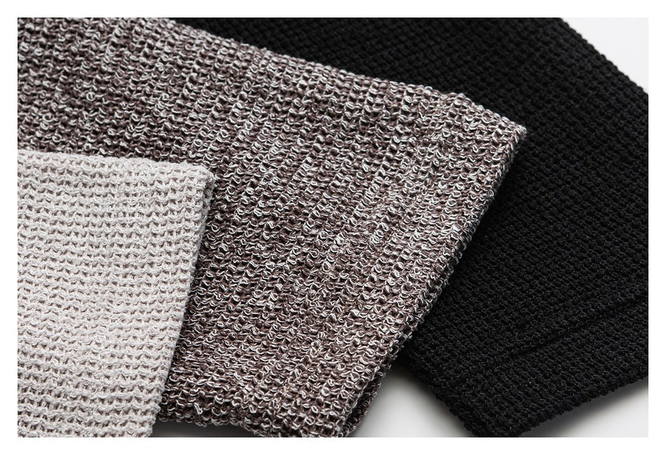 Close-up of three chunky knit colorways in light cream, taupe, and black.