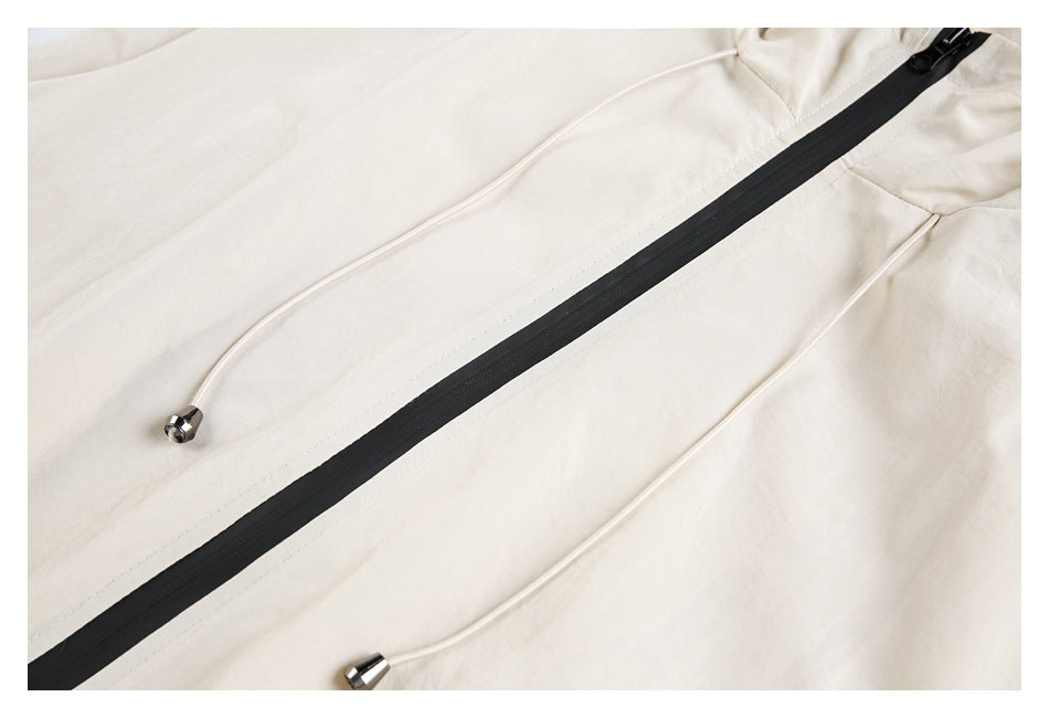 Close-up of the cream jacket's black front zipper and two cream drawcords with metal tips.