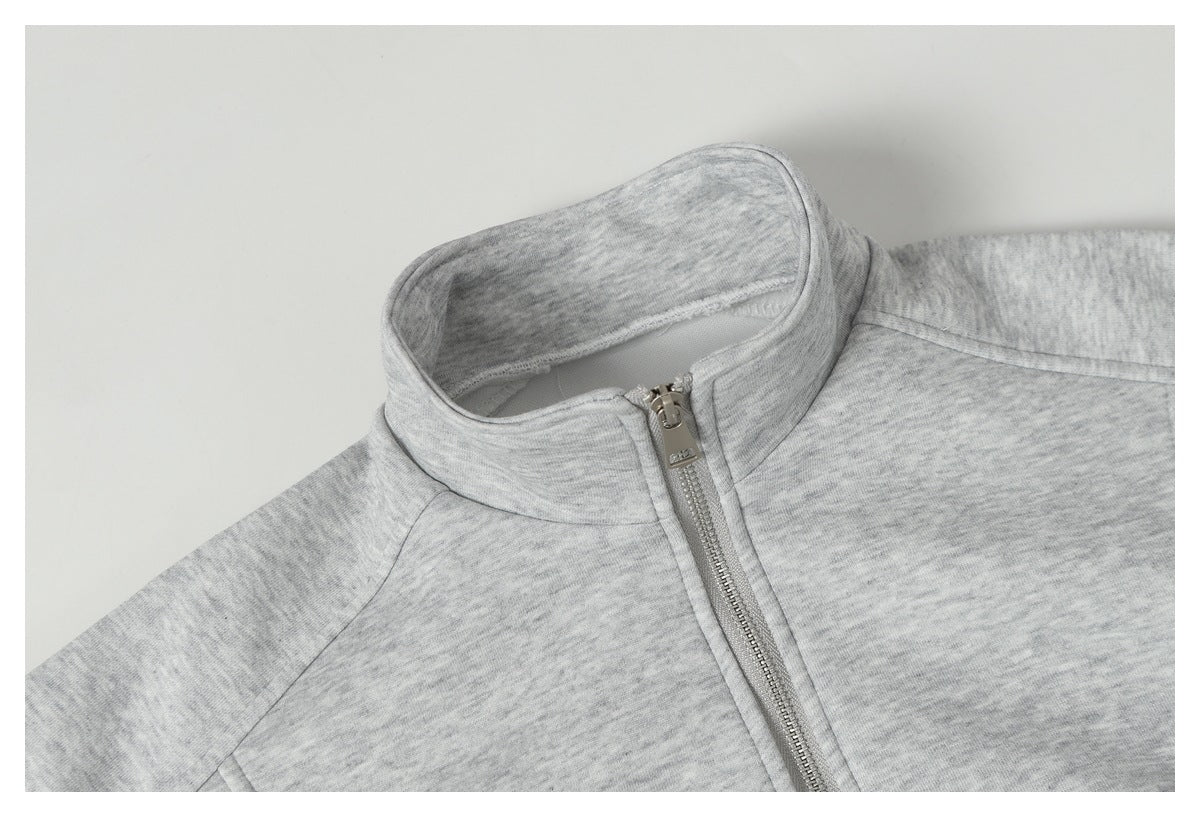 Close-up of a light gray heather zip-up jacket showing its raised collar, shoulder seam, and metal zipper.