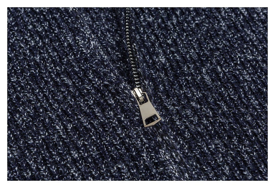 Close-up of a metal zipper on dark navy marled knit fabric.