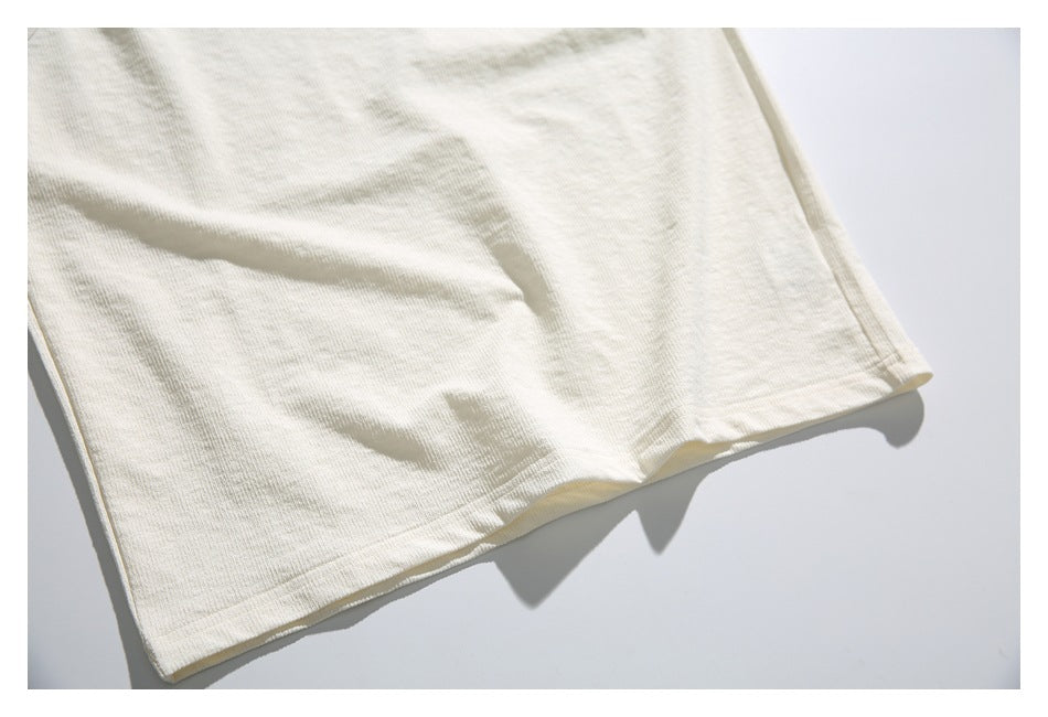 Close-up of the ivory top's lower body and stitched hem, laid flat.