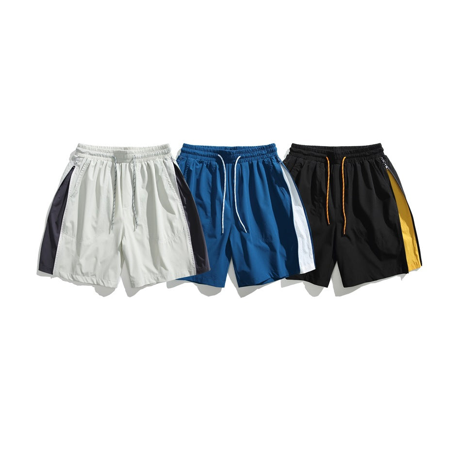 Three pairs of drawstring shorts in white with dark panels, blue with white panels, and black with yellow panels.