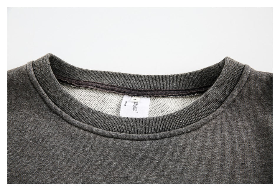 Close-up of the charcoal sweatshirt’s ribbed crew neckline and inner neck label.