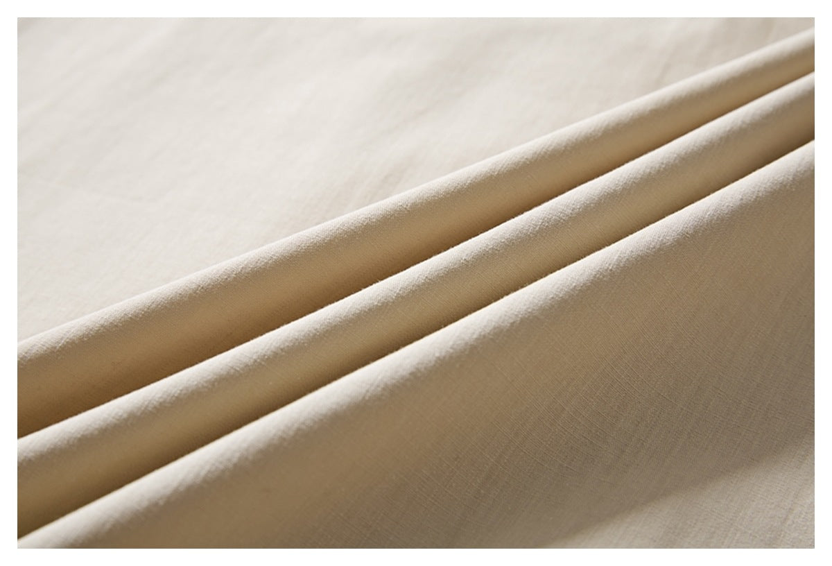 Close-up of ivory shirt fabric arranged in soft folds, showing its subtle woven texture.