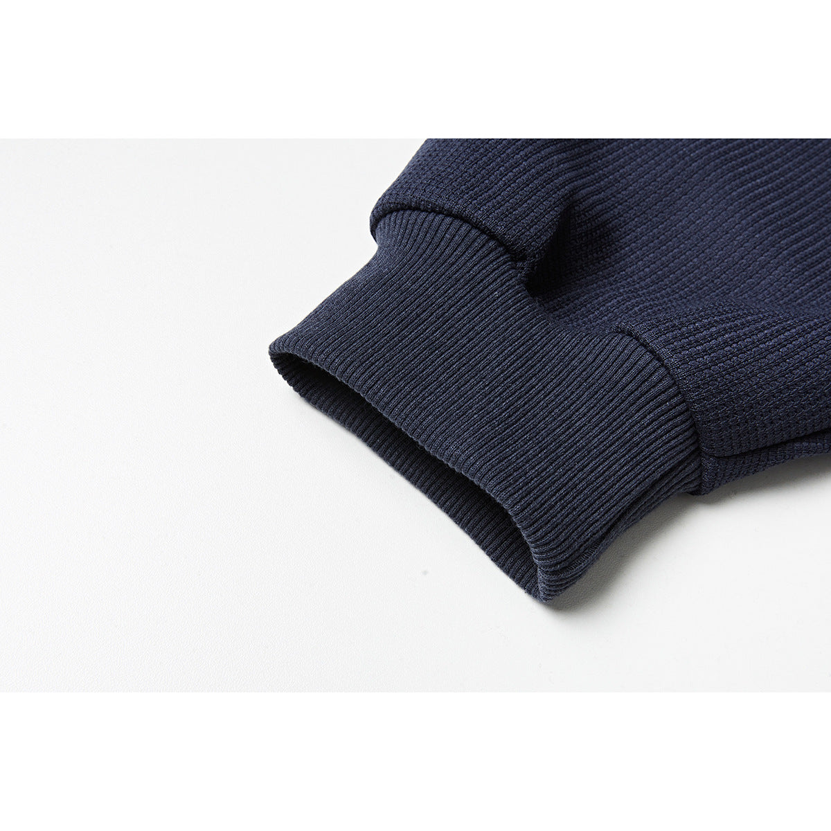 Close-up of a navy sweatshirt sleeve ending in a wide ribbed cuff.