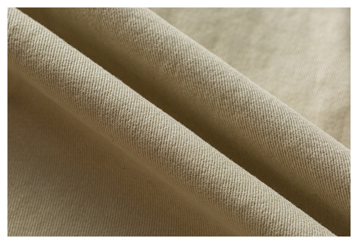 Close-up of beige twill fabric folded into ridges, showing its woven texture.