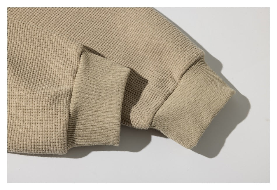 Close-up of a beige textured jacket sleeve with a wide ribbed cuff.