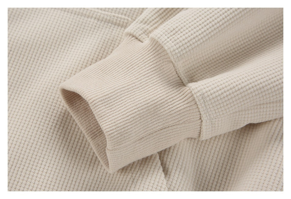 Close-up of a ribbed cuff on a cream waffle-textured garment.