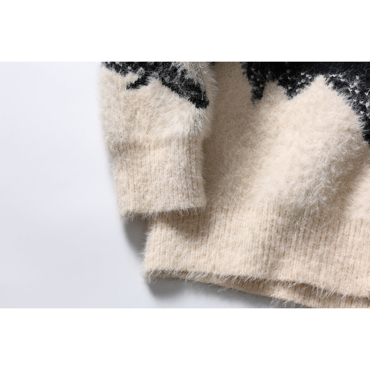 Close-up of an ivory ribbed sleeve cuff and cardigan hem, with part of the black and ivory pattern visible.