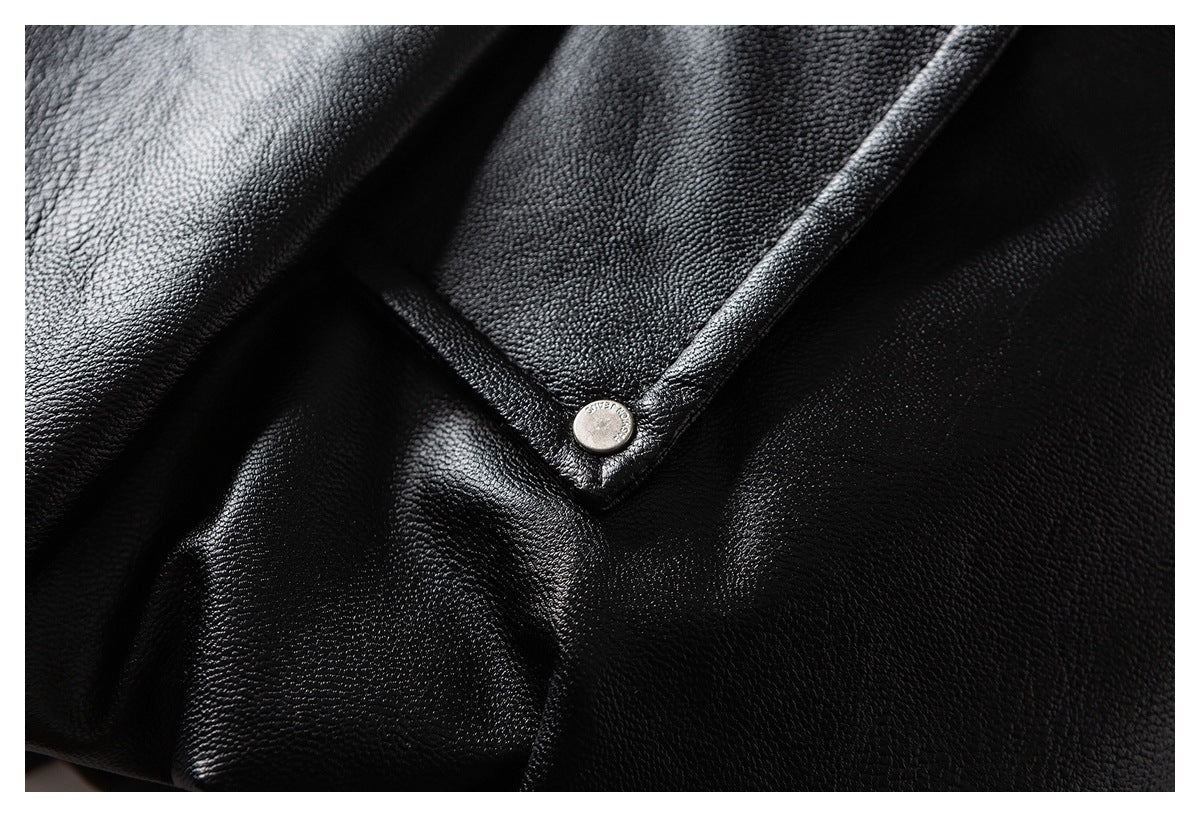 Close-up of black textured material and a stitched edge fastened with a round metal snap.