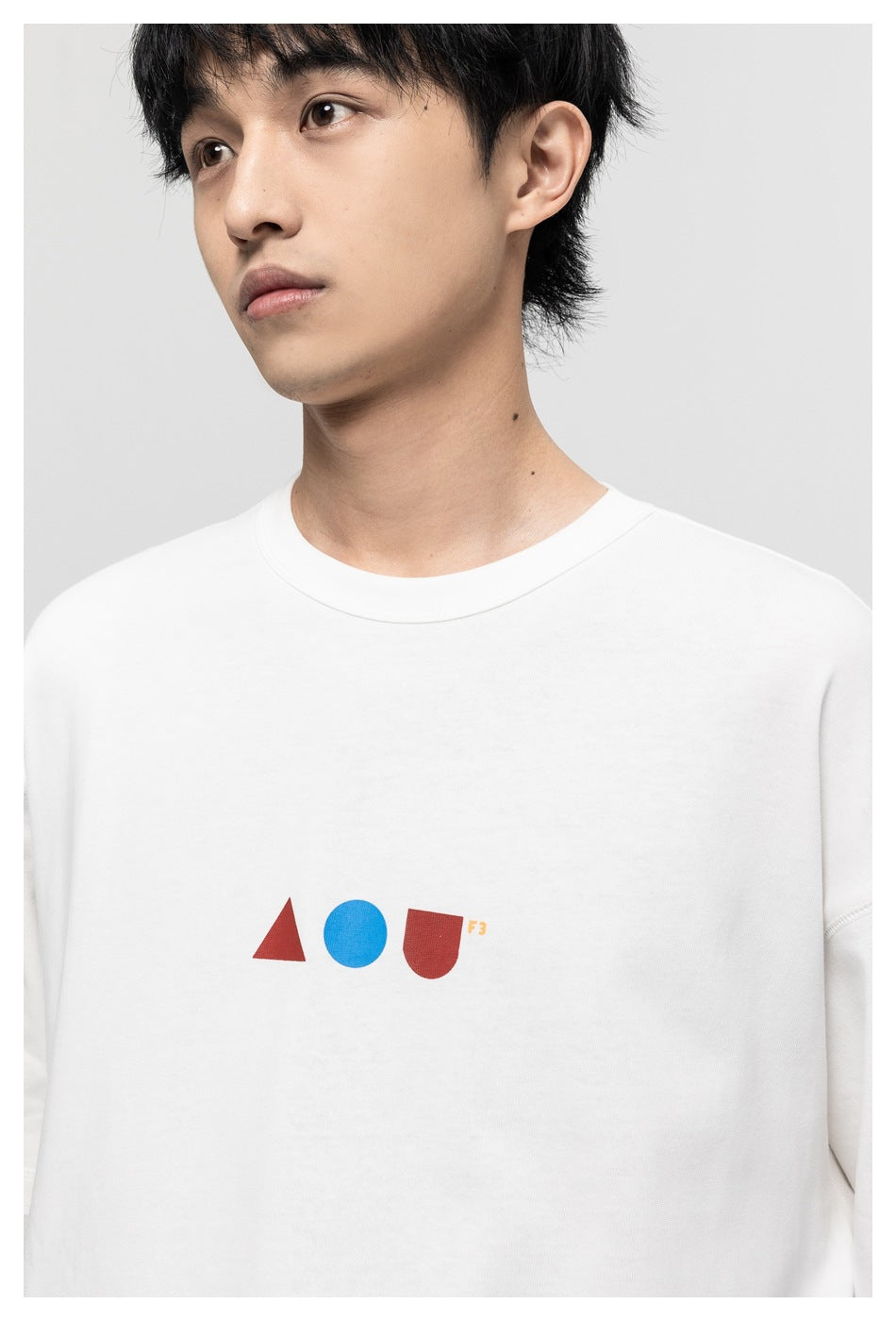 Close-up of a model wearing a white T-shirt, showing its red and blue geometric chest graphic.