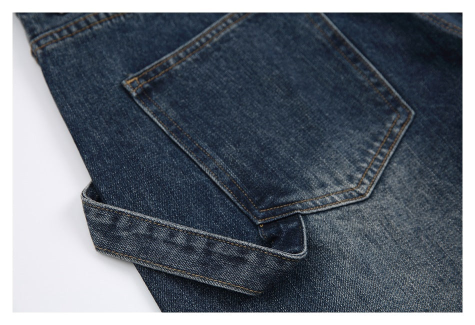 Close-up of dark blue denim jeans showing a back pocket, contrast stitching, and a folded section.
